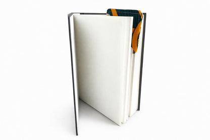 Black spiral-bound notebook with a cream, green, blue & orange corner bookmark on a light gray background