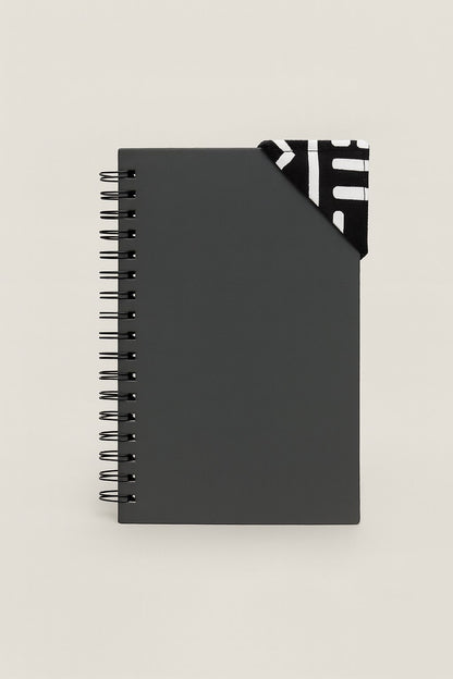 Black spiral-bound notebook with a black and white corner bookmark on a light gray background