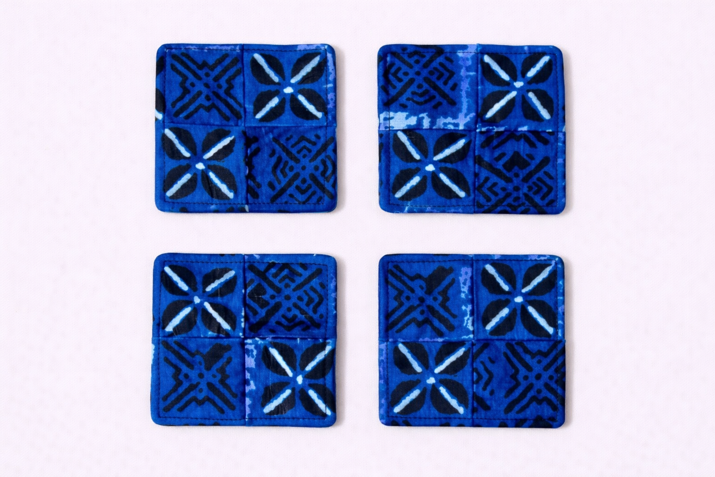 Set of 4 blue, black, & white African fabric coasters on white background