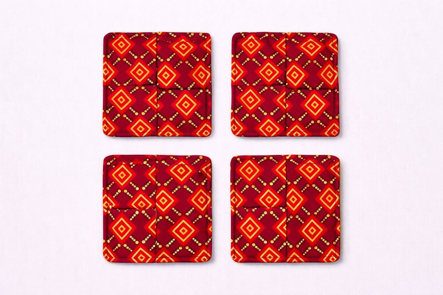 Set of 4 maroon, red, black, & gold African fabric coasters on white background