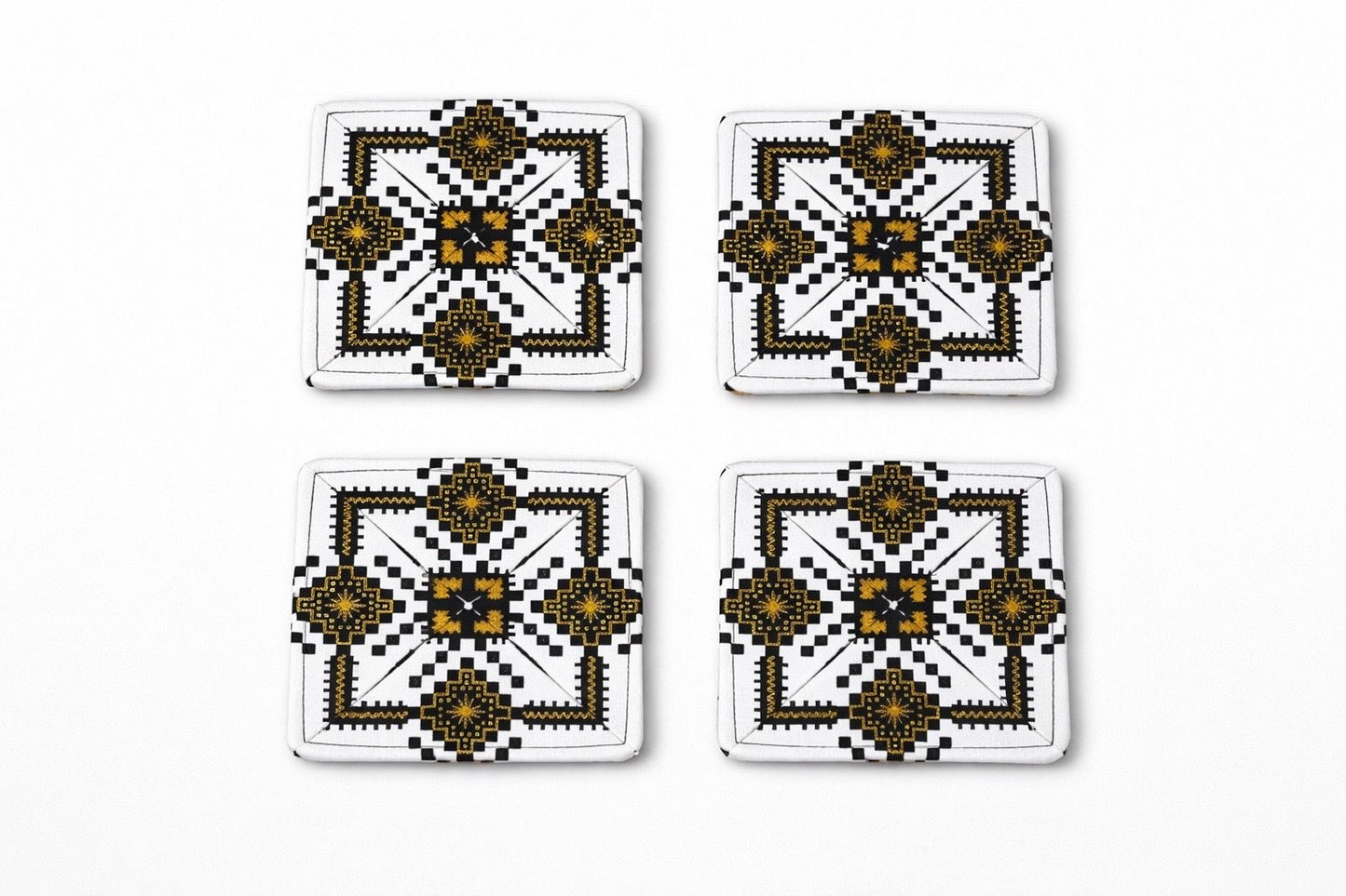 Set of 4 white, black, & gold African fabric coasters on white background
