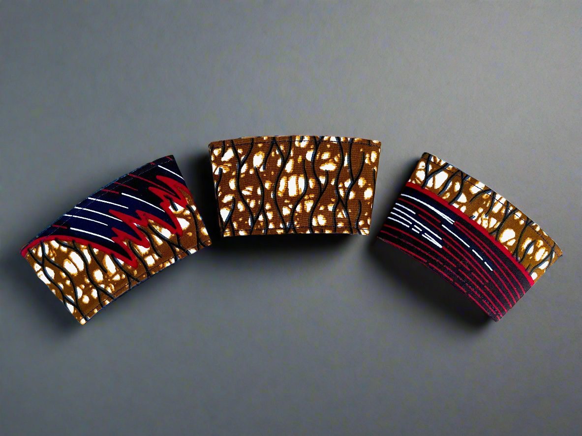 Three flat cream, dark blue, brown, red, & white cup sleeves on a dark grey background