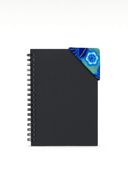 Black spiral-bound notebook with a dark blue, blue, white, & gold corner bookmark on a light gray background