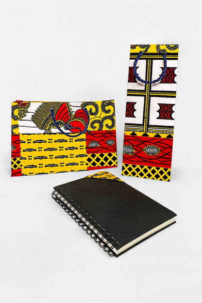 Red, white, dark blue, and yellow medium horizontal gift bag, wine gift bag, and bookmark on a spiral notebook on a white background